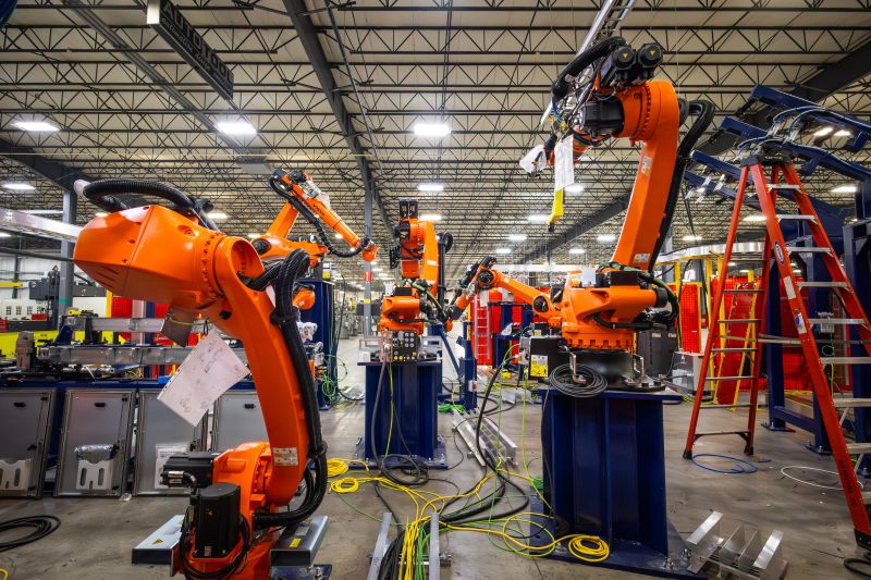 KUKA industrial robots installed in an automotive production environment, performing automated welding and handling operations within asystem-integrated workcell