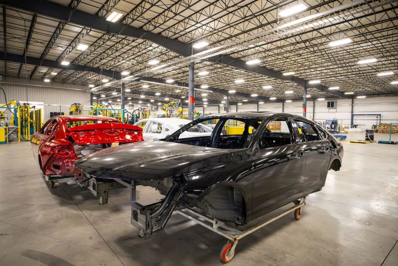 Automotive body structures staged on an assembly floor, illustrating vehicle manufacturing workflows supported by automated welding and material handling systems