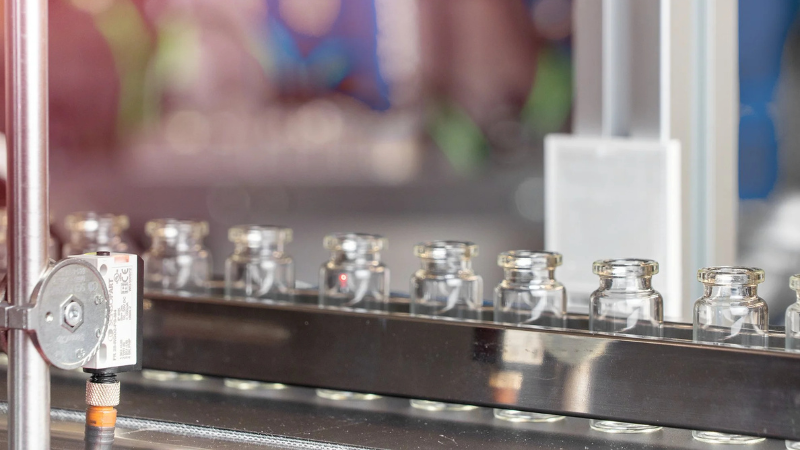 A diffuse light sensor being used to detect clear bottles on a conveyor belt